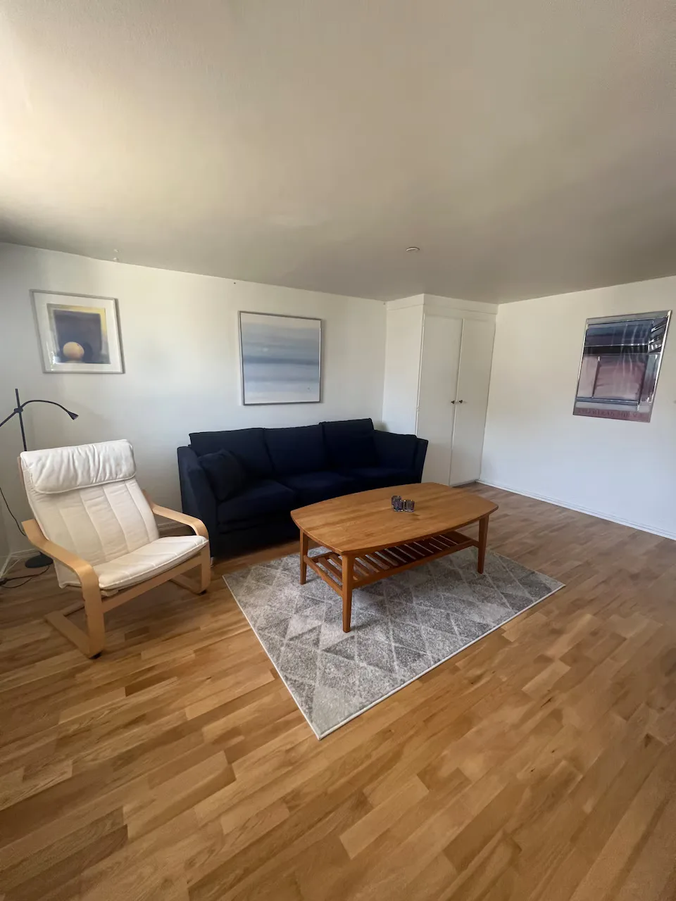 Ljust vardagsrum med soffa, fåtölj och soffbord